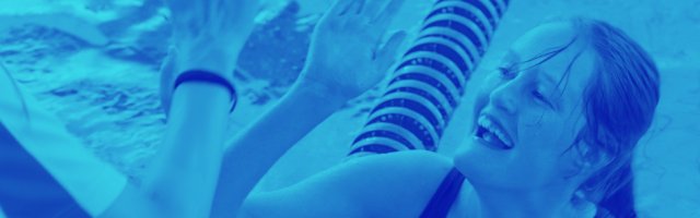 young-girl-in-swimming-pool-at-the-edge-high-fiving-with-a-coach