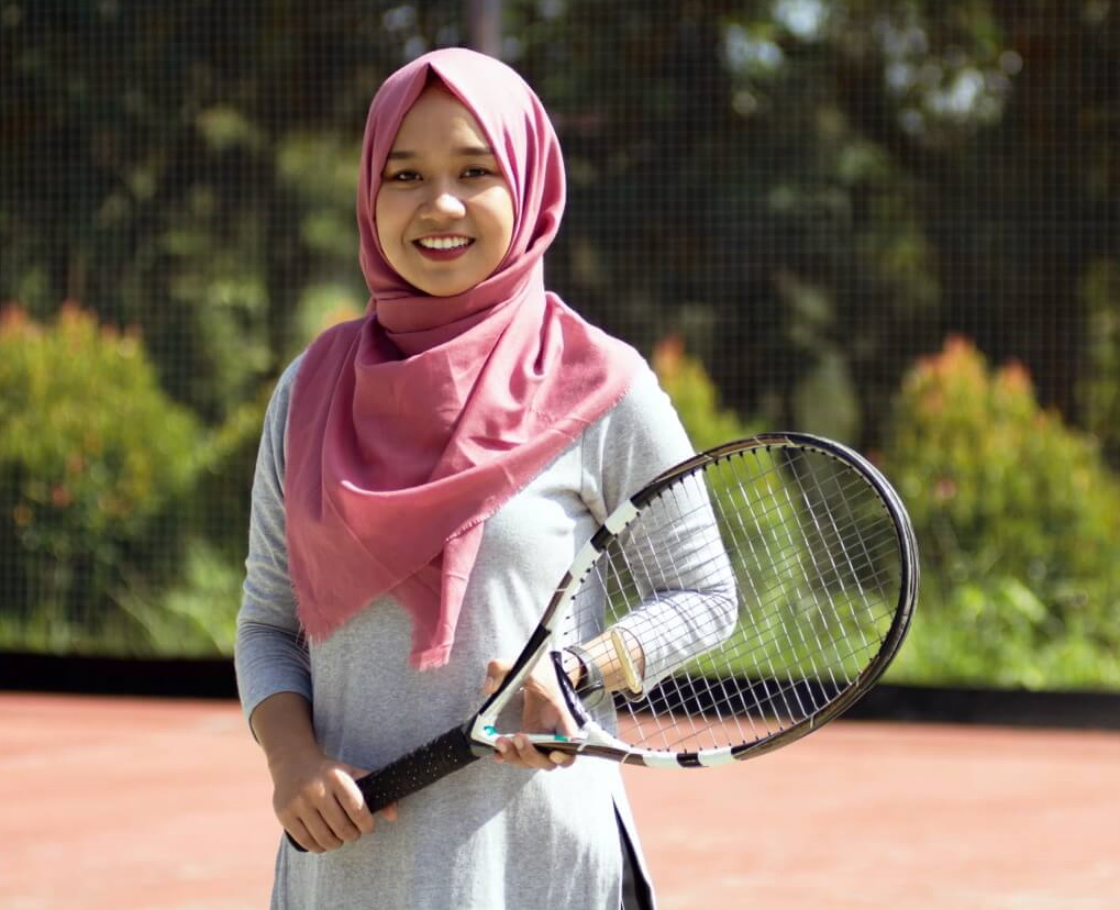 Girl wearing a hijab holding a tennis racquet