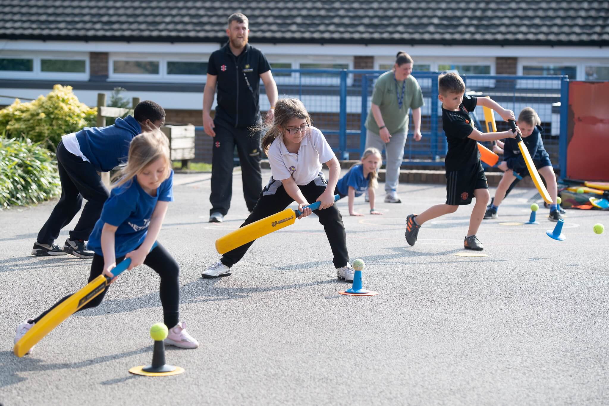 A line of children practise hitting the cricket ball off a batting tee