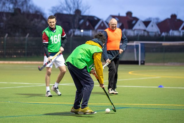 young-boy-playing-hockey-with-a-coach-in-shot-on-a-hockey-pitch