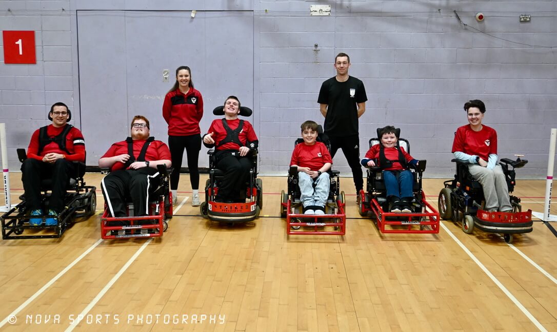 Group of smiling wheelchair users with their coaches