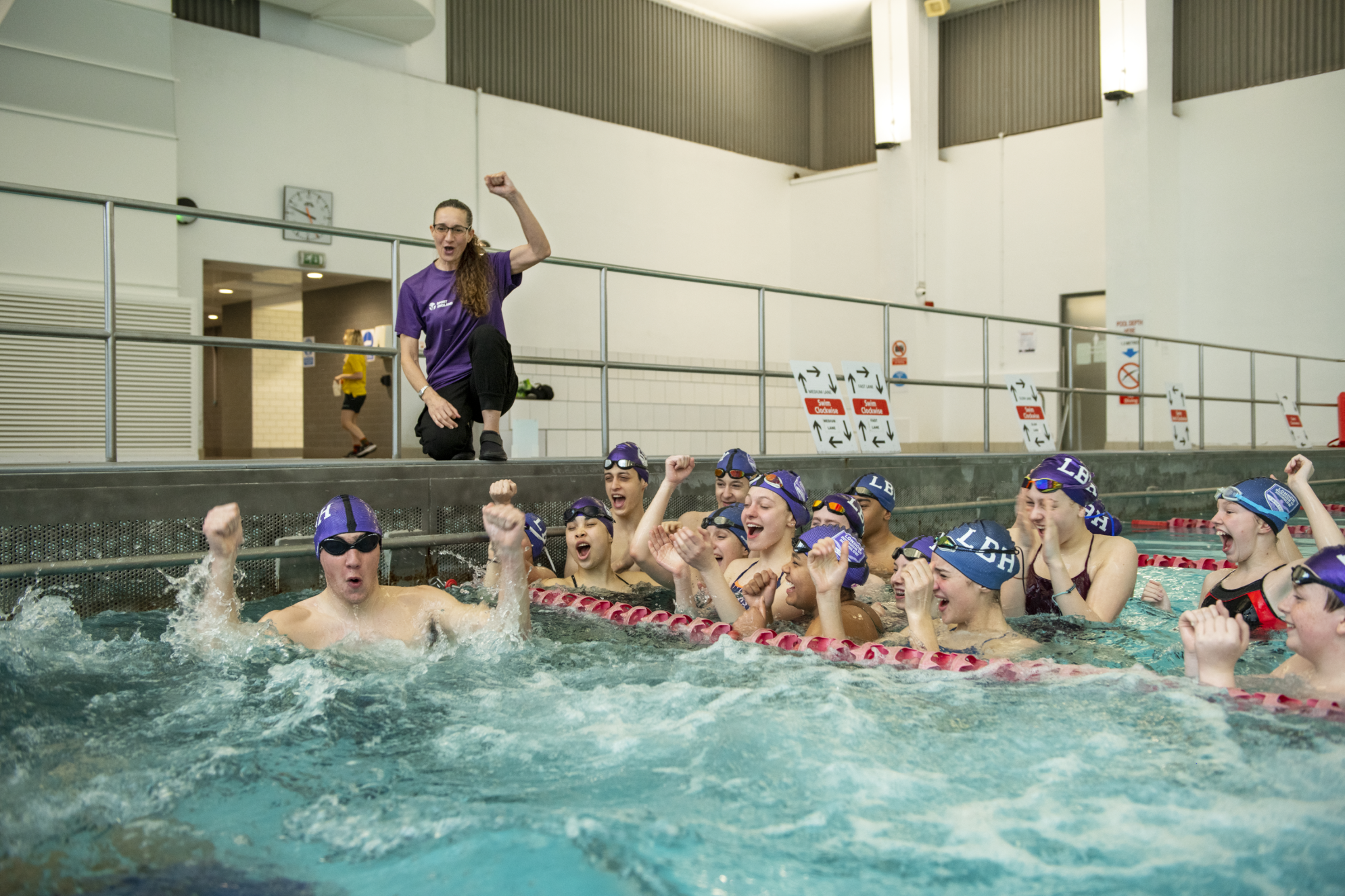 Swimming coach Lisa celebrating with kids at the poolside