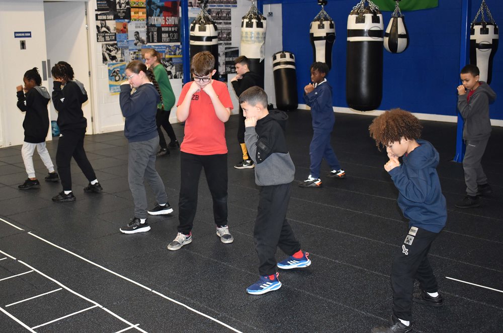 Young boxers line up in two rows to practice their jabs and footwork