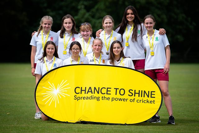 Group of smiling girls standing behind a Chance To Shine sign