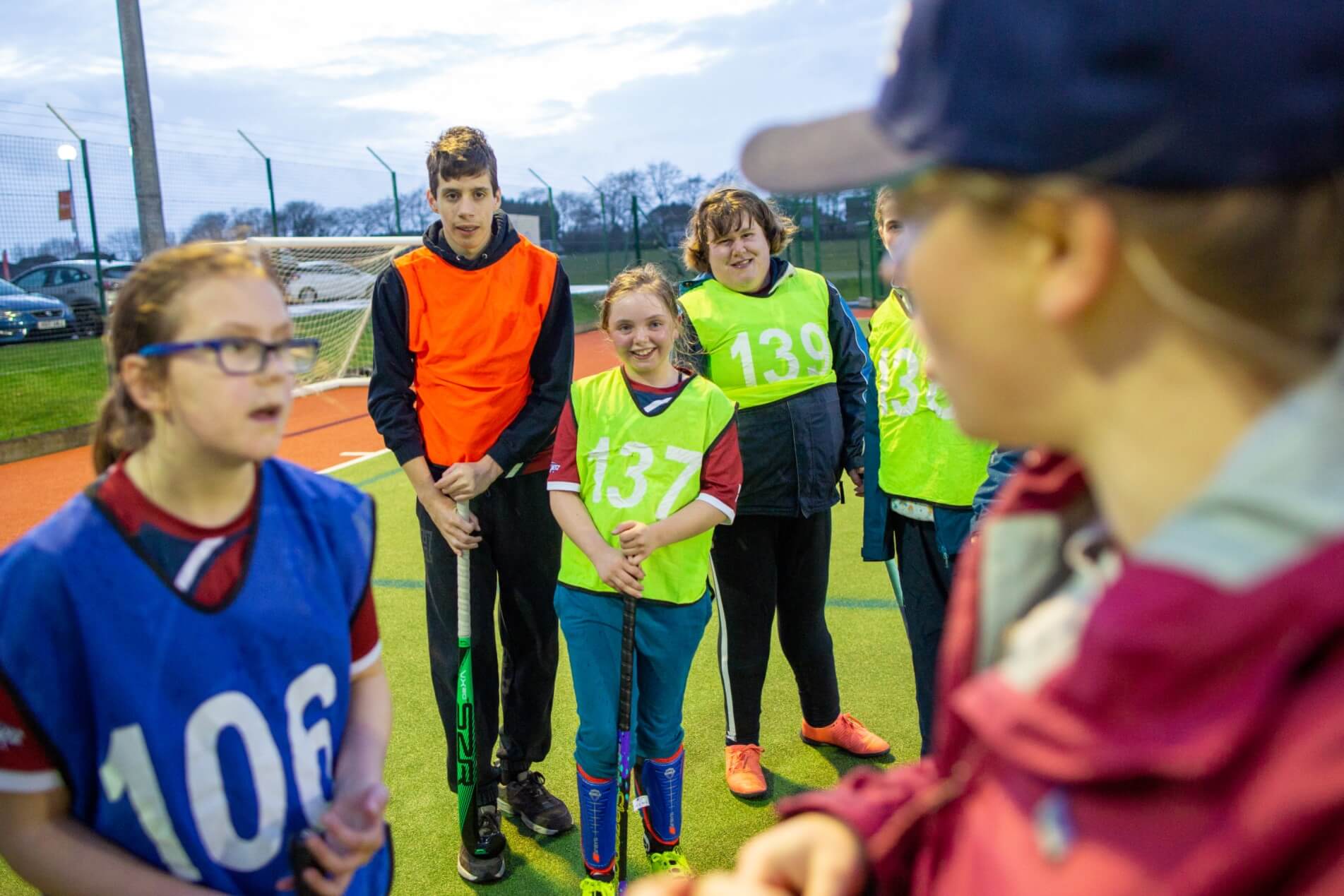 Young girl wearing glasses and a blue bib talks to her coach