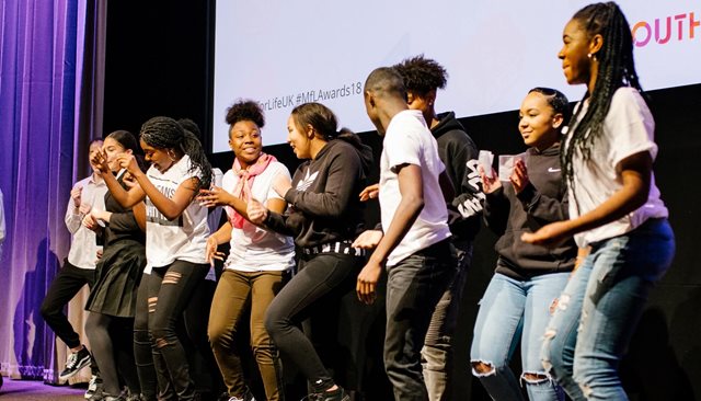 Group of young people on stage dancing at an awards ceremony