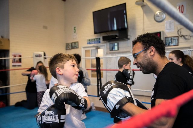 Young Boy Throwing Punches at Boxing Pads
