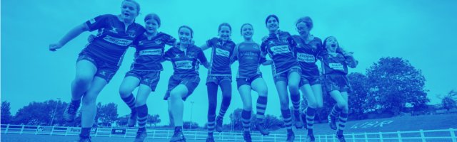 group-of-girls-on-a-rugby-pitch-linking-arms