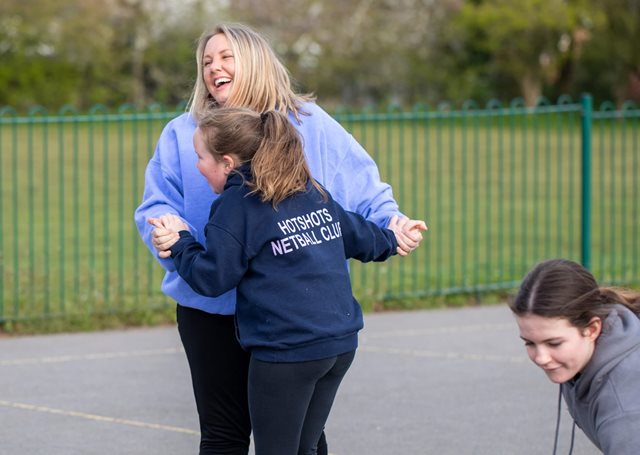 Coach and child laughing together on a netball court