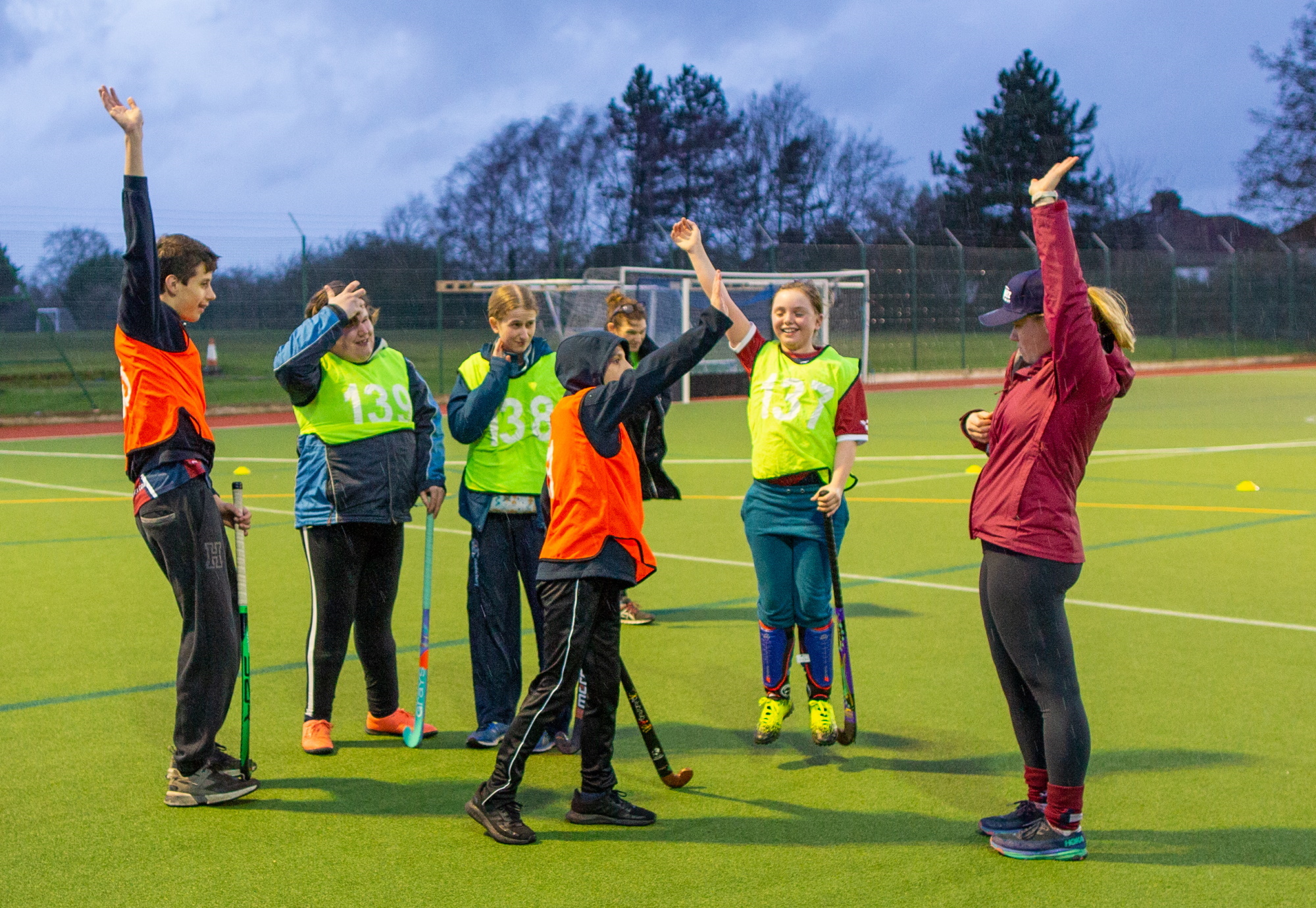 Hockey players raise their hands in the air looking towards their coach