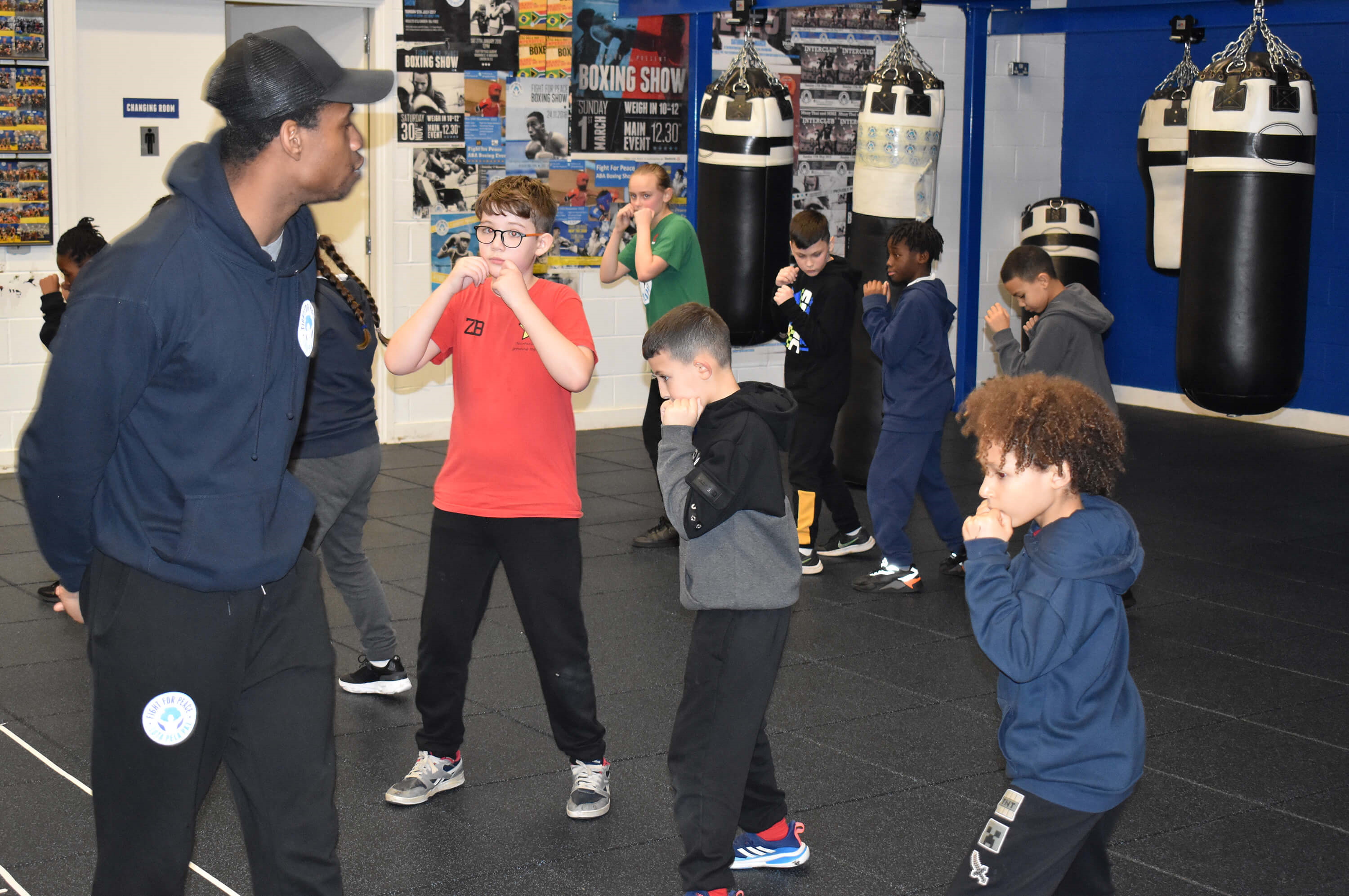 Boxing coach walks in front of his participants passing on advice and encouragement as they train