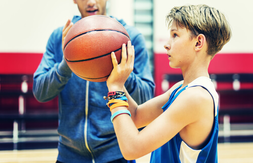 Teenage boy about to shoot a basketball hoop inside a sports hall