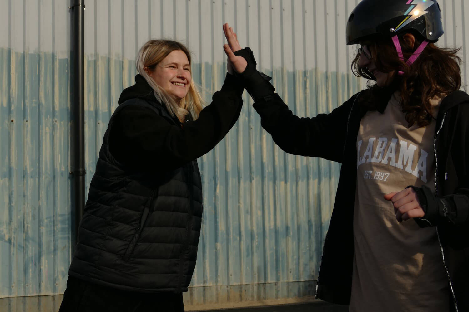 Elsie the skateboard coach gives a high five to a young person. 