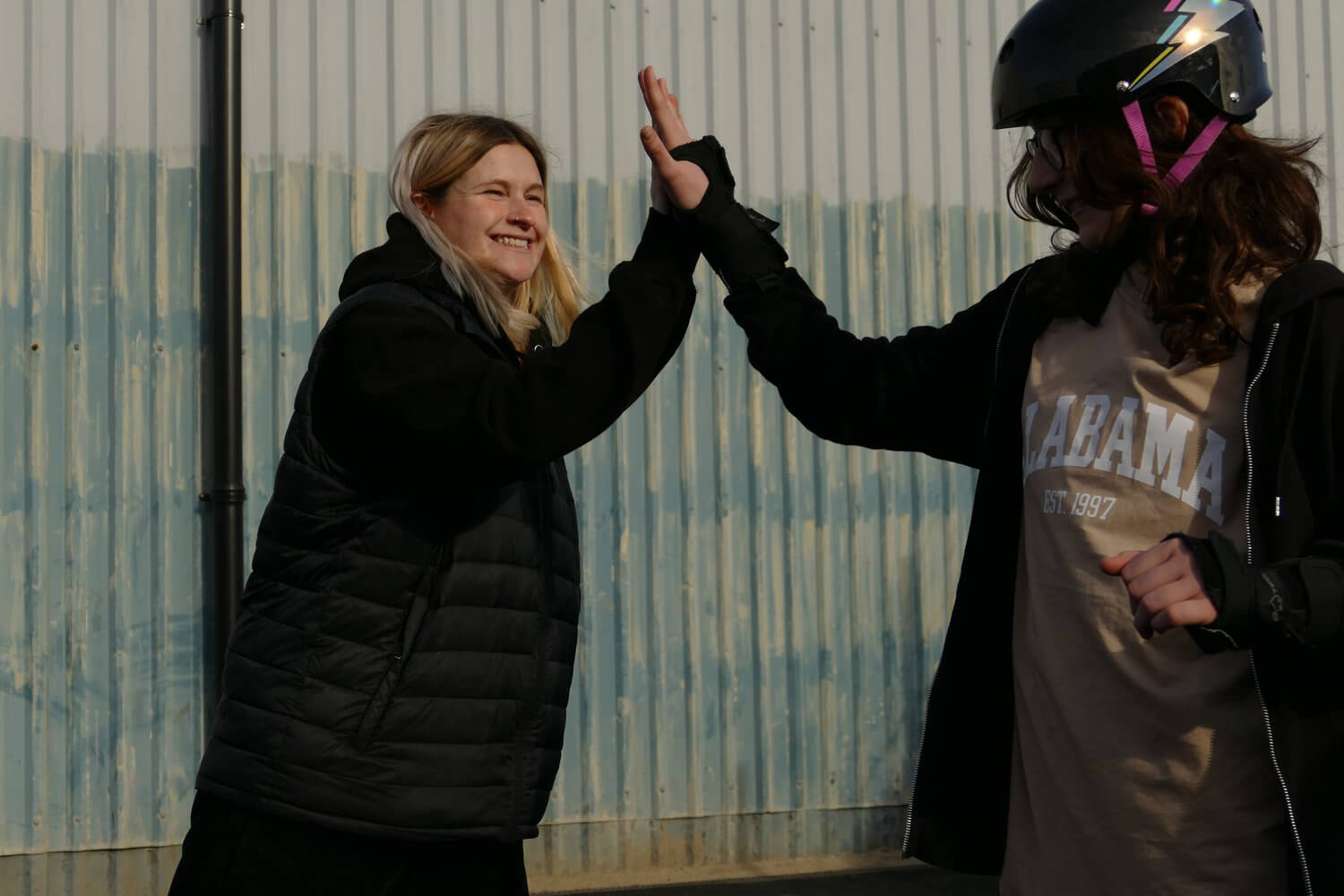 Elsie the skateboard coach gives a high five to a young person.
