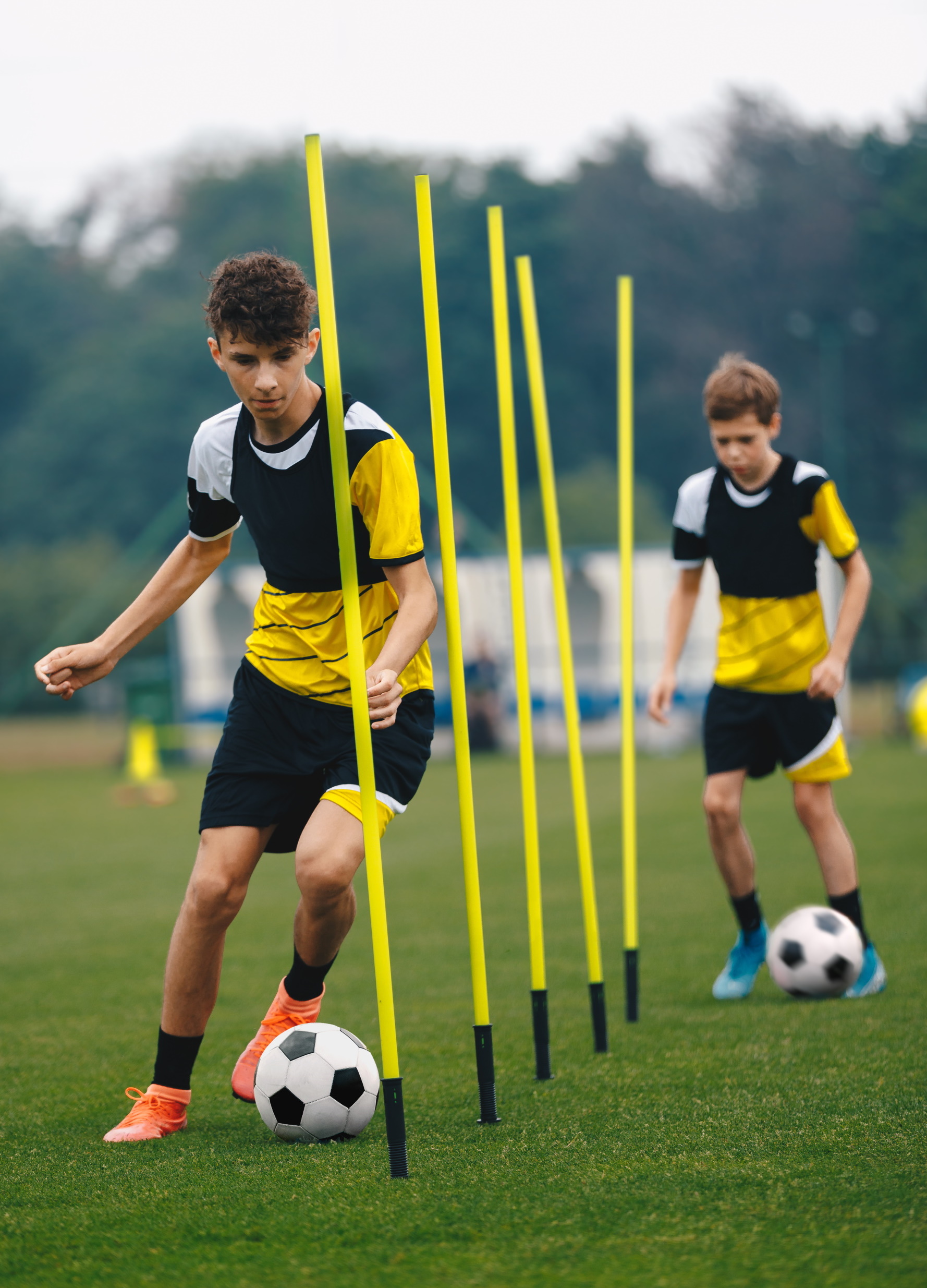 A footballer dribbles round some markers