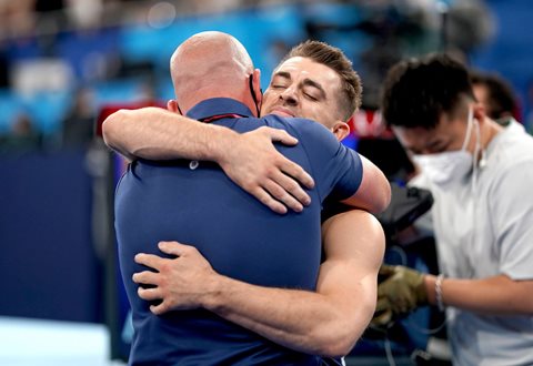 Coach and gymnast embrace at the end of their performance at the Olympic Games