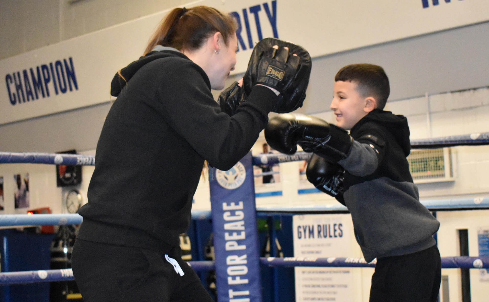 A young boxer delivers a jab on the pads during training with their coach in the ring