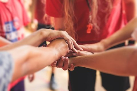 Group of young people with their hands in a hand stack.