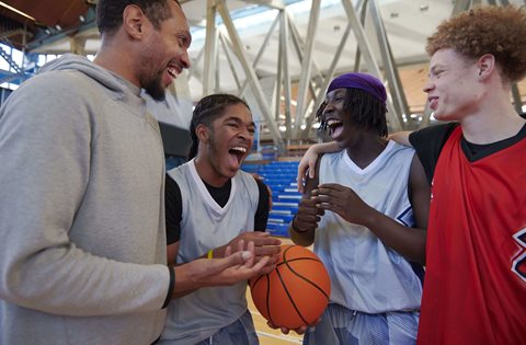 basketball players laughing with coach