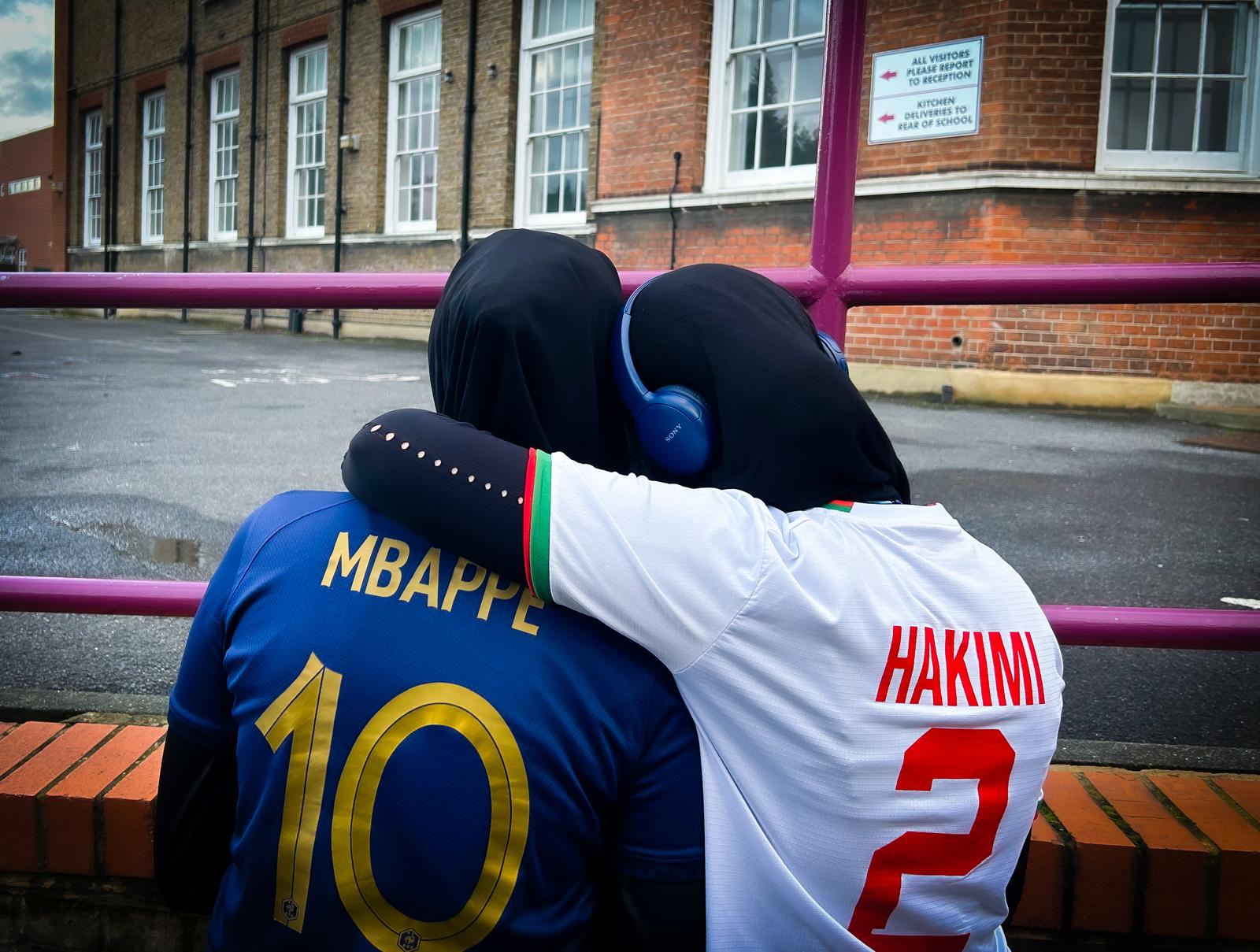two-muslim-girls-with-their-backs-to-camera-hugging-in-a-playground
