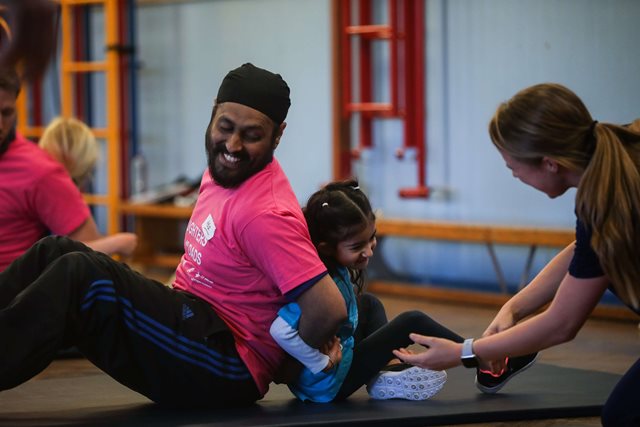 Dad playing sport with a girl supported by a female coach