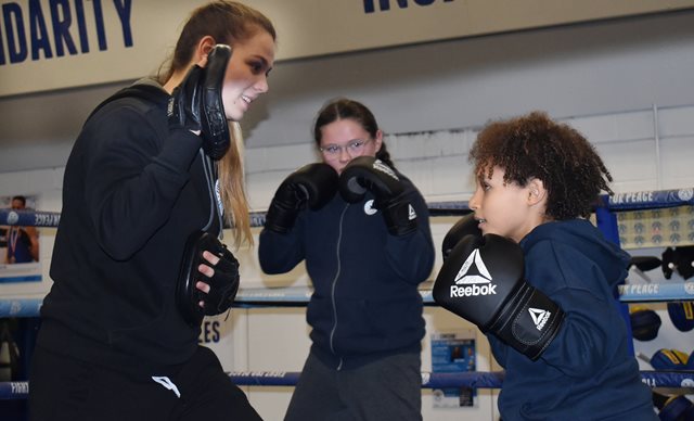 A young boxer taking part in pad work training with their coach in the boxing ring