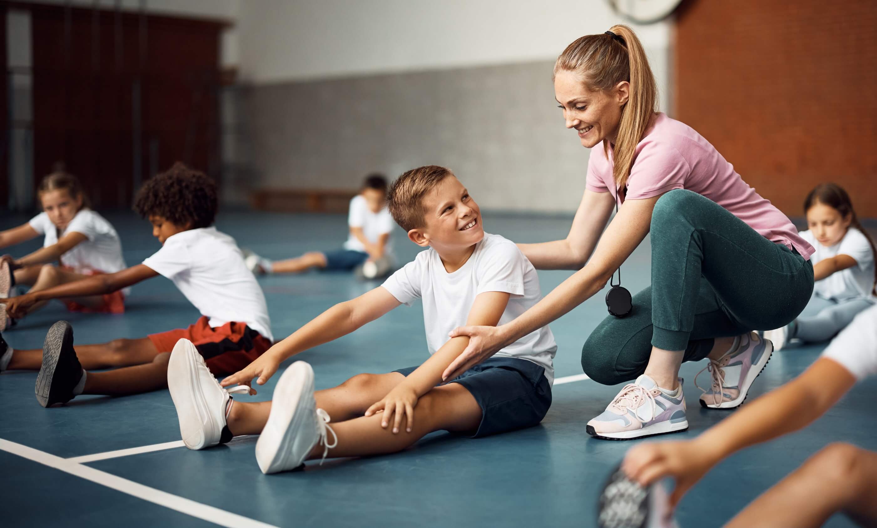 Sports coach leading a group in a stretch indoors