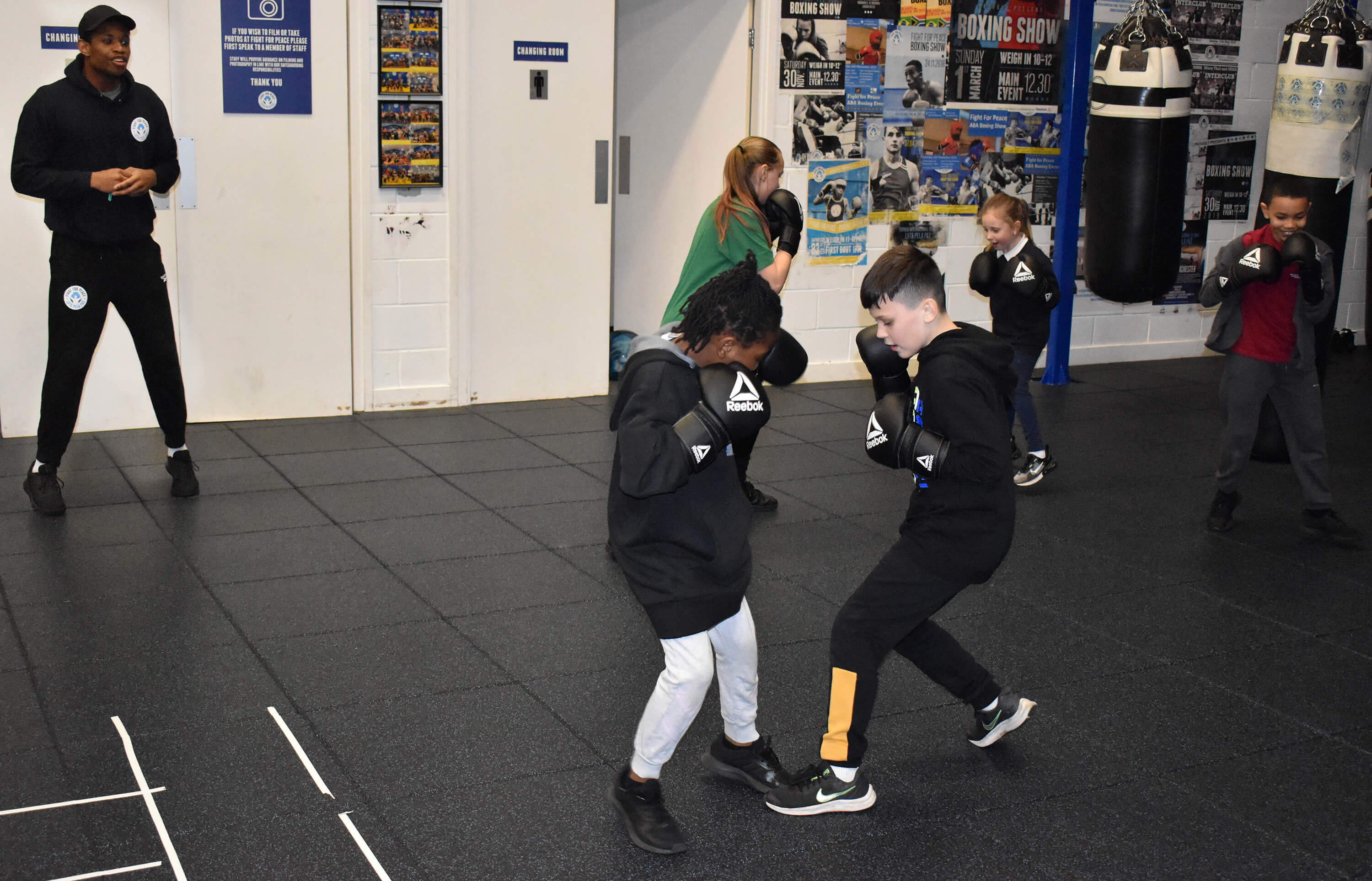Young boxers in groups of two involved in a drill where one boxer has to step on the toes of their opponent 
