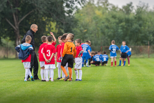 Boys football team huddled for a team talk with coach on the football pitch