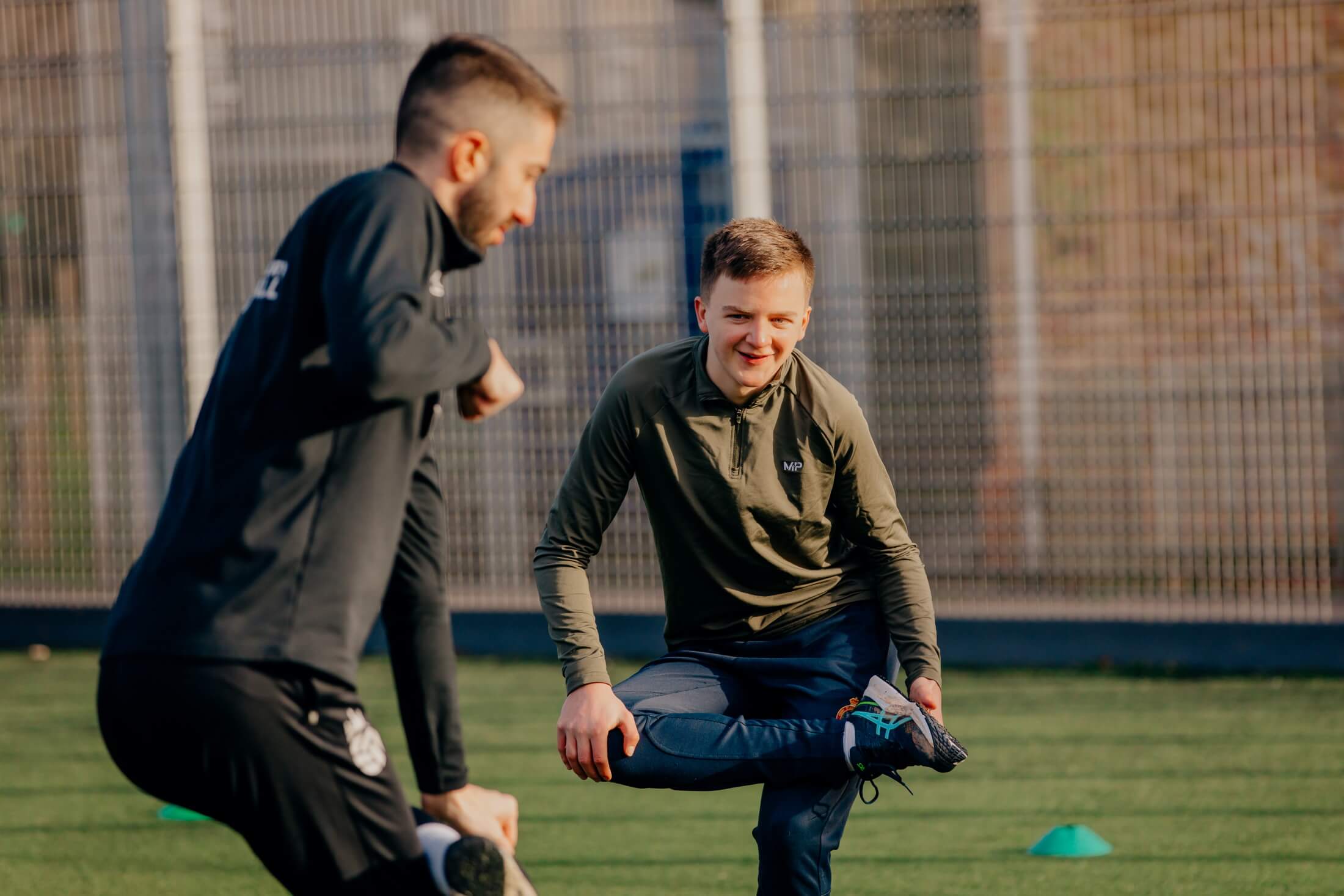 A coach leads a warm-up involving bending your leg and touching the inside of your right foot
