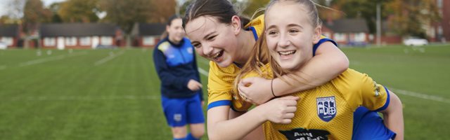 One girl giving another girl a piggyback at a session