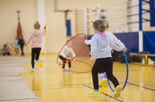 young girls playing with hula hoops in a gym session