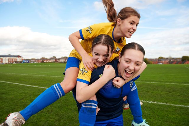 Teenage girls celebrating and playing football