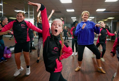 Girls dancing with coach in the background