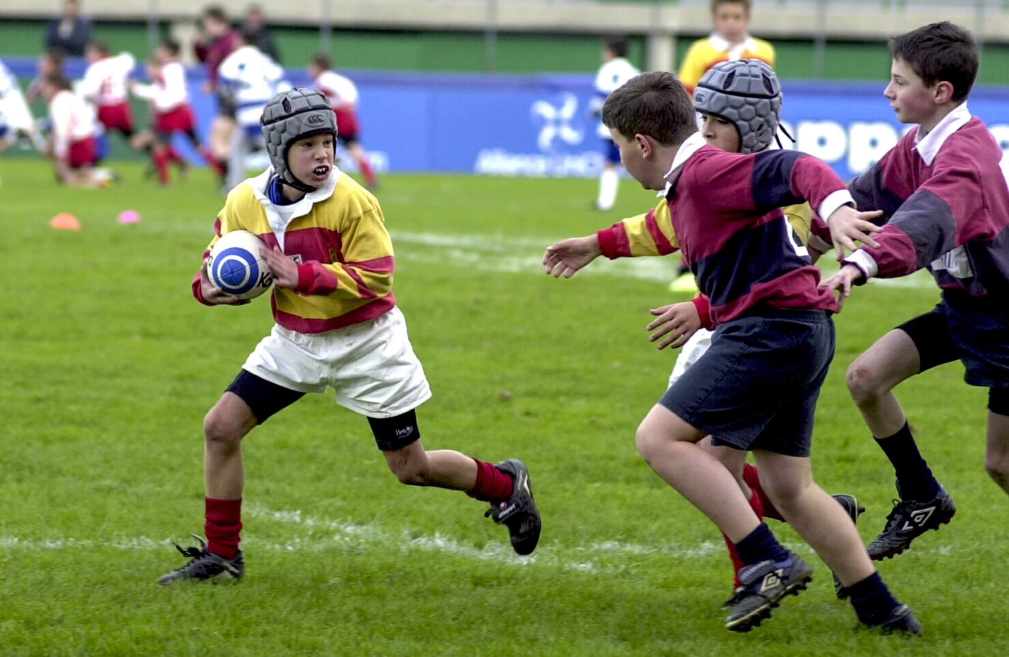 Rugby player runs with the ball pursued by opposing players during a match
