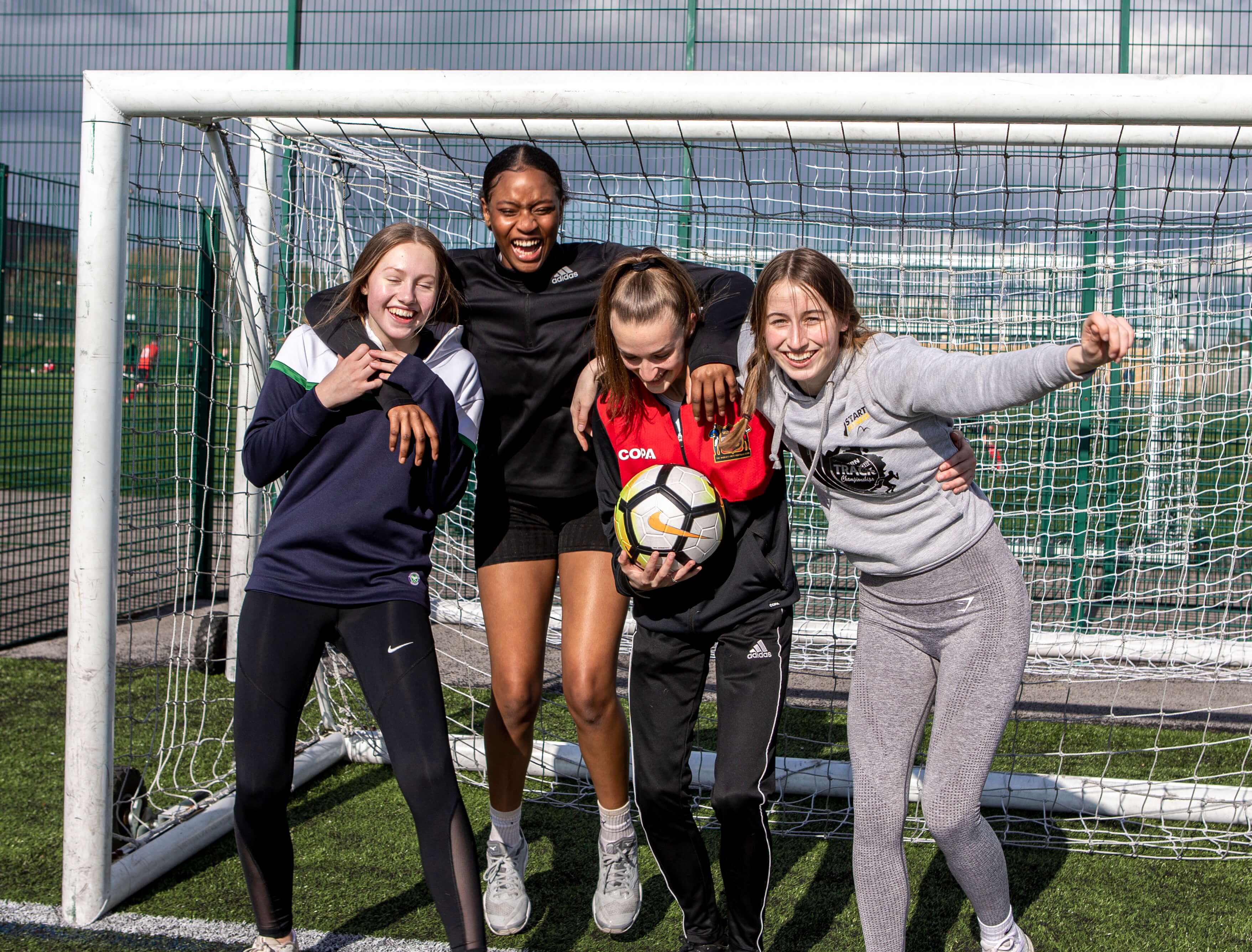Girls laughing together at a session, one holding a football