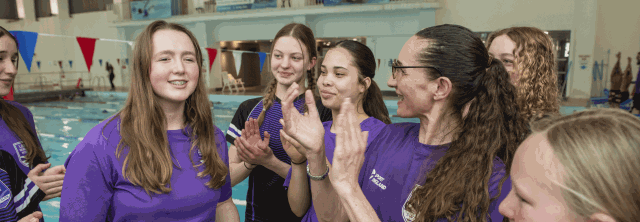 Swimming group are clapping by the poolside.