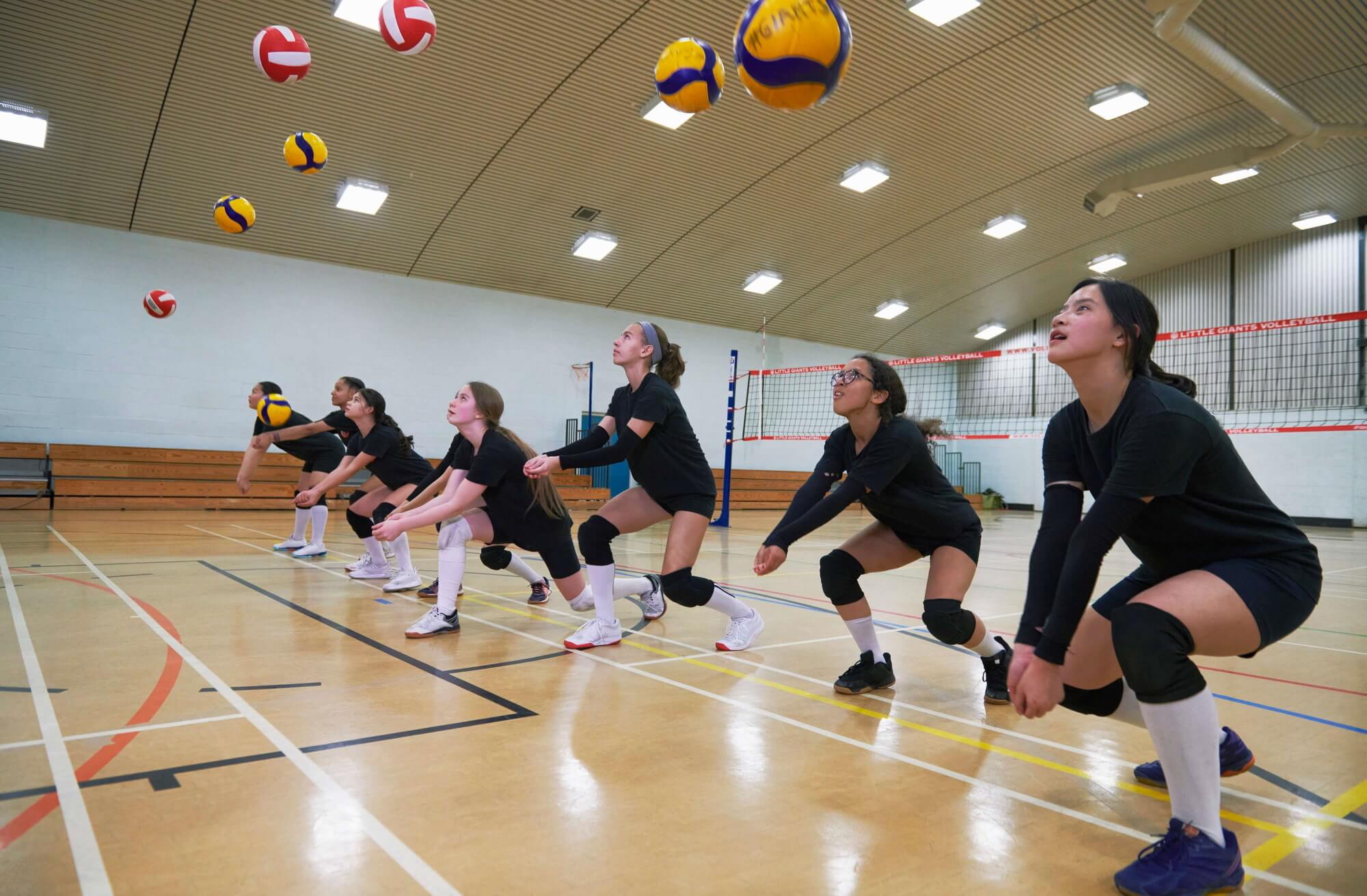 Teenagers playing volleyball in a sports hall