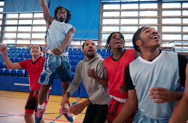 Happy teenage basketball team celebrating a victory on the court
