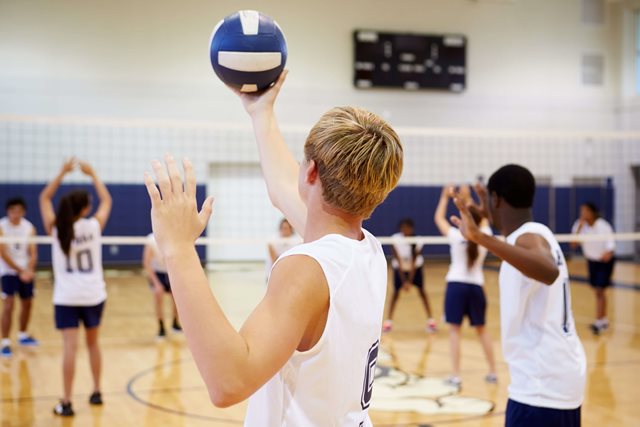 Teenagers playing volleyball in a sports hall